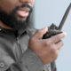 Male security guard using portable radio transmitter outdoors